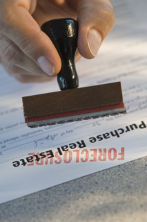 Man stamping “foreclosure” on mortgage form.
