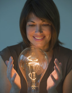 Woman holding hands around large light bulb.