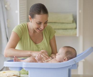 Mother bathing baby son in baby bathtub.