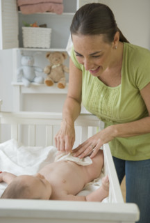 Mother changing baby son’s diaper.