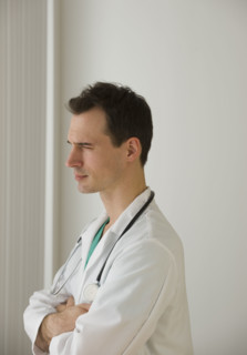Male doctor looking out window pensively.
