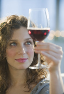 Woman examining coloring of red wine.