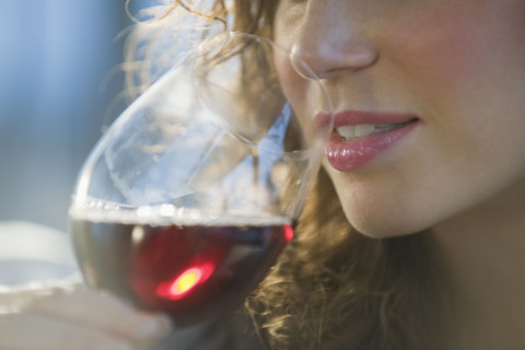 Close up of woman smelling red wine.