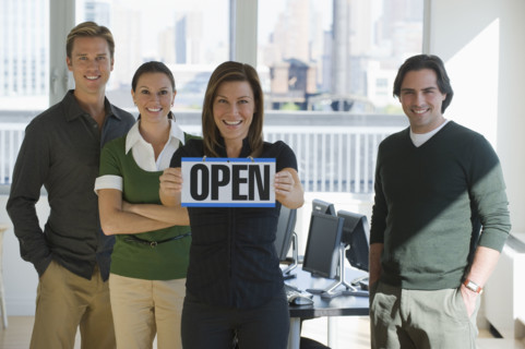 Portrait of business people holding ”Open” sign.