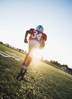 Football player running on field with football. Date : 2008