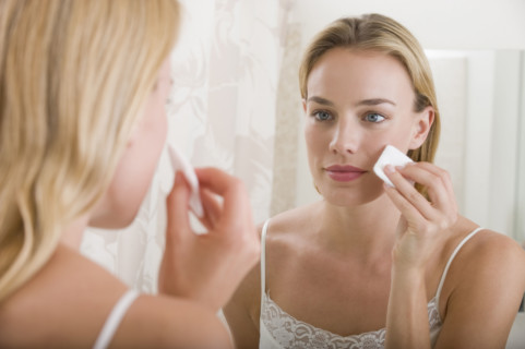 Woman applying makeup in bathroom.