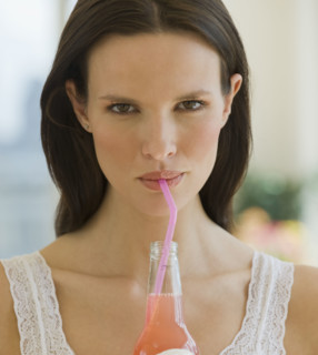 Close up of woman drinking soda from a straw.