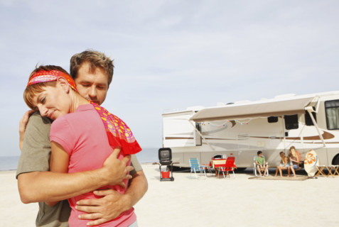 Couple hugging on beach with motor home in background. Date : 2008