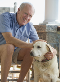 Portrait of senior man sitting on porch with dog.