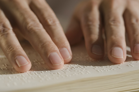 Close up of hand reading braille.