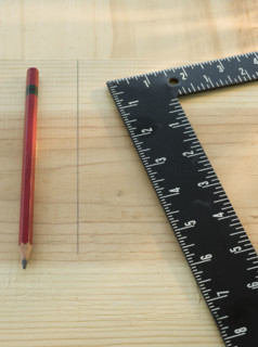 Pencil and carpenter’s rule on wood plank.