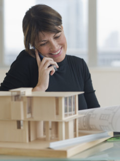 Architect talking on cell phone next to building model.