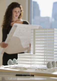 Architect viewing blueprints near building model.