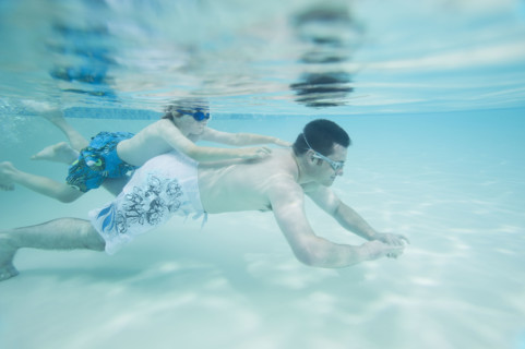 Boy swimming on father’s back underwater. Date : 2008