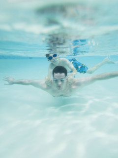 Boy swimming on father’s back underwater. Date : 2008