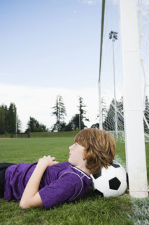 Boy laying on soccer ball against goal. Date : 2008
