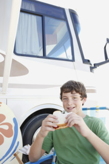 Portrait of boy eating sandwich outside motor home. Date : 2008