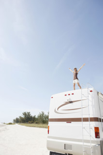 Woman standing on motor home with arms outstretched. Date : 2008