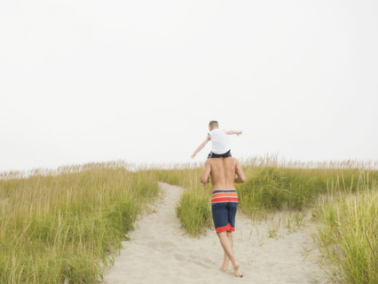 Father carrying son on shoulders at beach. Date: 2008