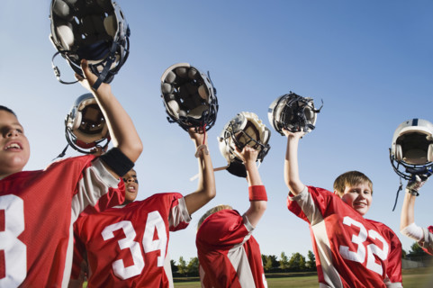 Football team holding helmets overhead. Date: 2008