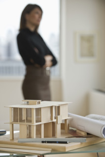 Building model and blueprints with architect in background.