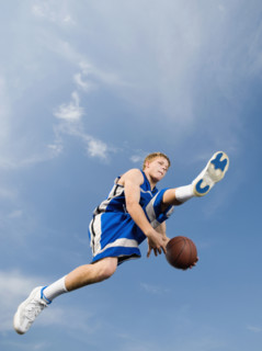 Teenage basketball player in mid-air with basketball. Date : 2008