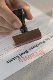 Man stamping “approved” on mortgage application.