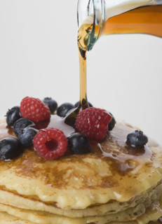 Close up of maple syrup being poured on pancakes.