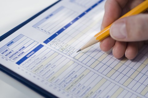 Man writing on budget sheet.
