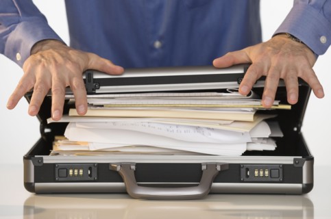 Businessman trying to close briefcase.