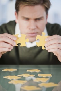 Businessman looking at puzzle pieces.