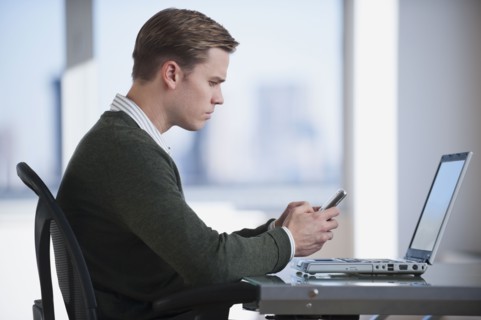 Businessman text messaging in office.