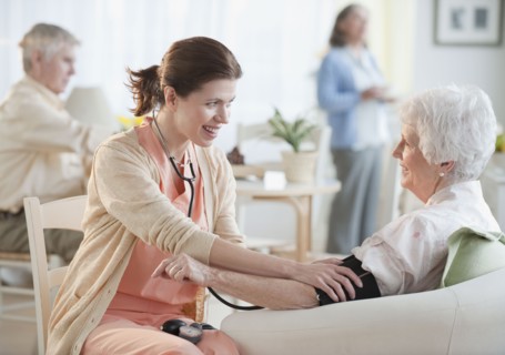 Nurse taking senior woman’s blood pressure.