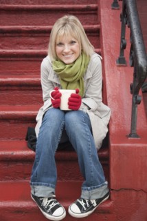 Woman drinking hot chocolate on front stoop. Photographe : Jamie Grill