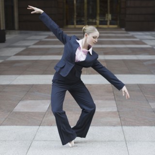 Businesswoman dancing in urban setting. Photographe : PT Images