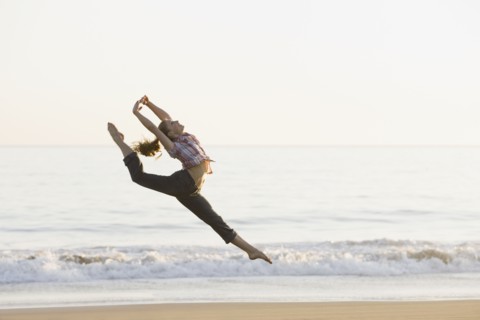 Woman dancing on beach. Photographe : PT Images