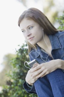 Young woman listening to mp3 player. Photographe : PT Images