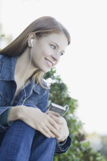 Young woman listening to mp3 player. Photographe : PT Images