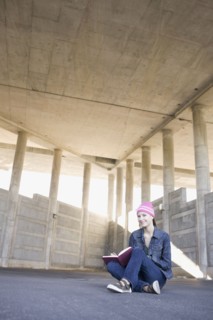 Young woman reading in urban setting. Photographe : PT Images