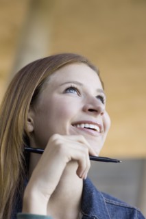 Young woman holding pen. Photographe : PT Images