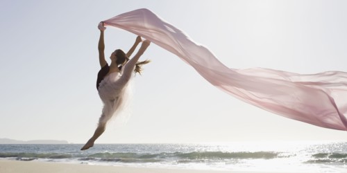 Dancer leaping on beach. Photographe : PT Images