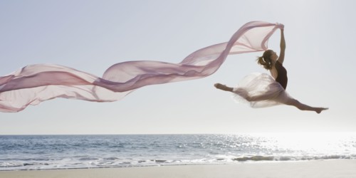 Dancer leaping on beach. Photographe : PT Images