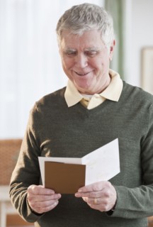 Senior man reading greeting card.