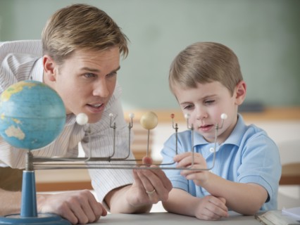 Teacher and student looking at globe.