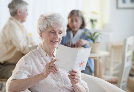 Senior woman reading greeting card.