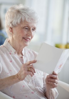 Senior woman reading greeting card.