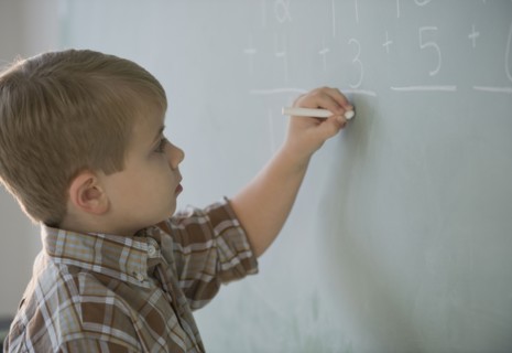 Boy doing math on blackboard.