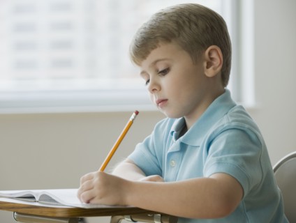 Boy writing in classroom.