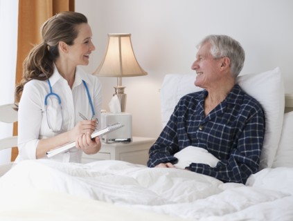 Nurse caring for senior man in bed.