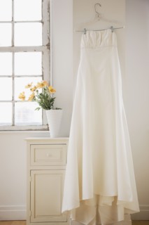 Wedding dress hanging in bed room. Photographe : Jamie Grill